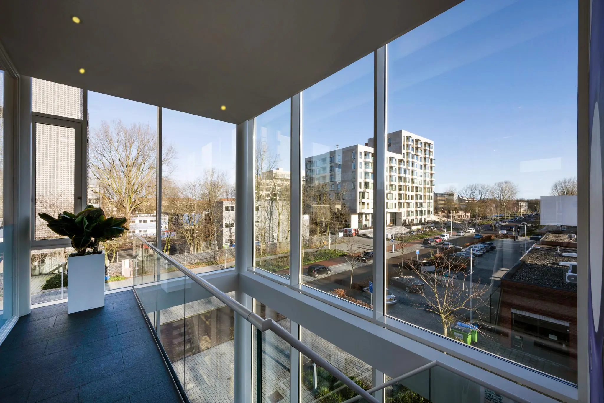 Uitzicht vanuit een modern gebouw aan de Fred. Roeskestraat op een straat met geparkeerde auto's en moderne appartementengebouwen.